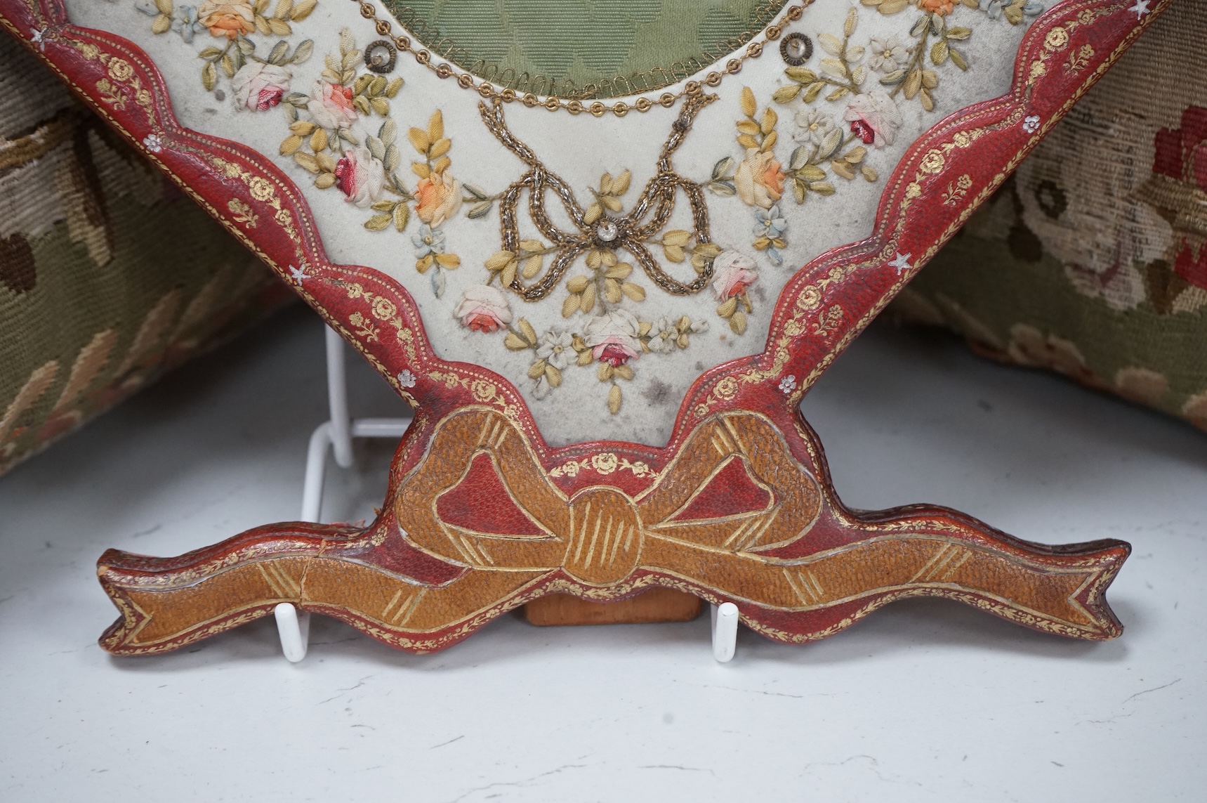 An Edwardian decorative stamped gilt leather photo frame, with bow to base and a floral patterned ribbon and sequin work front panel. 27.5cm high. Condition -good